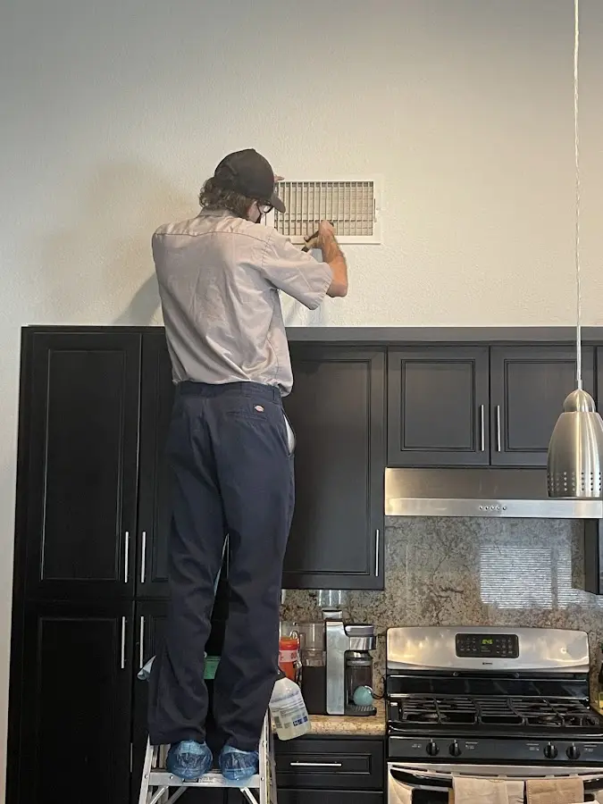 Technician inspecting an air vent during HVAC service in Fraser